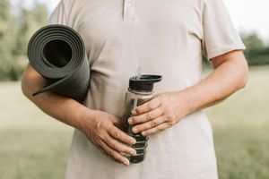 Close-up of a neatly rolled yoga mat and a water bottle.